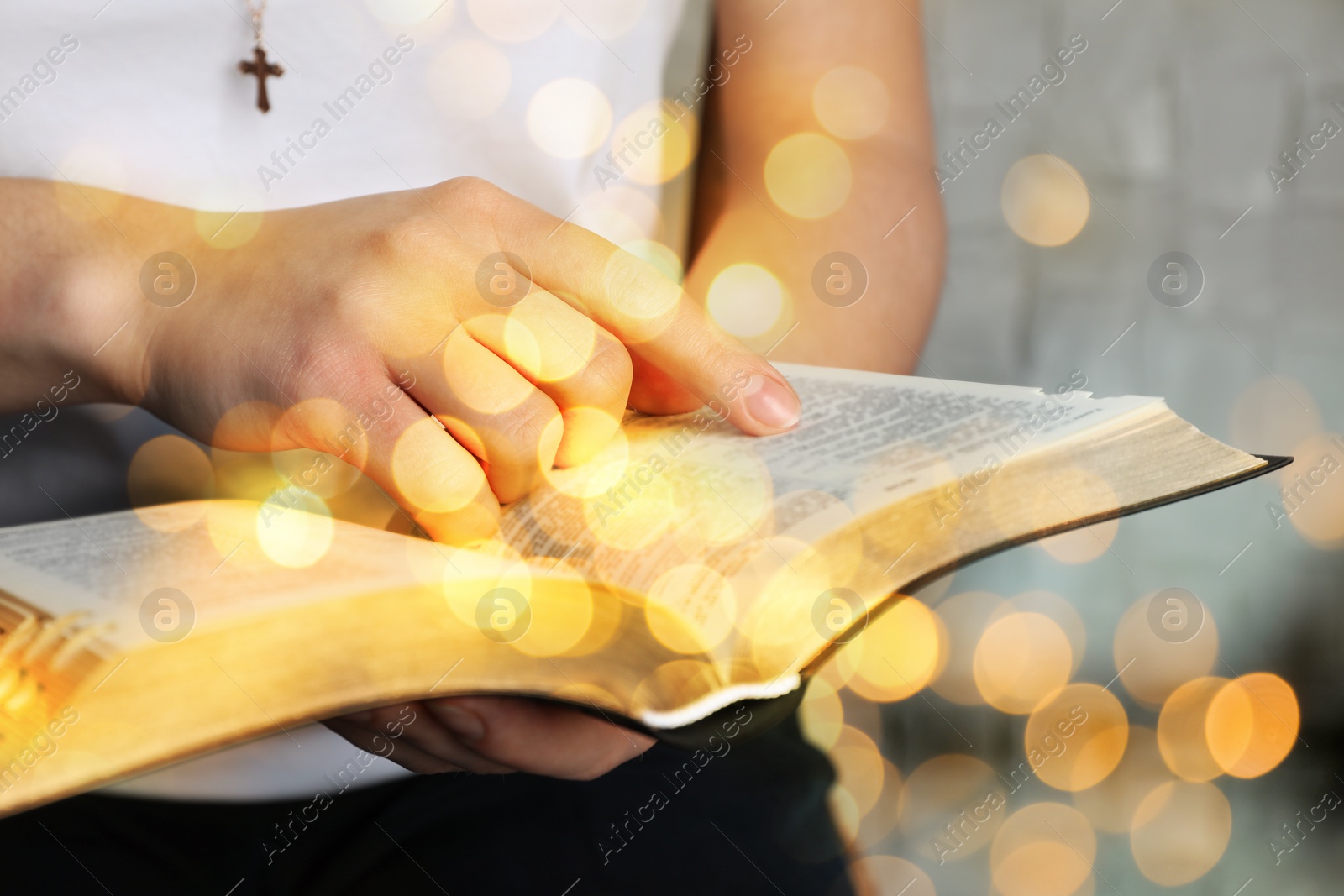 Image of Woman reading Bible near white wall, closeup. Bokeh effect