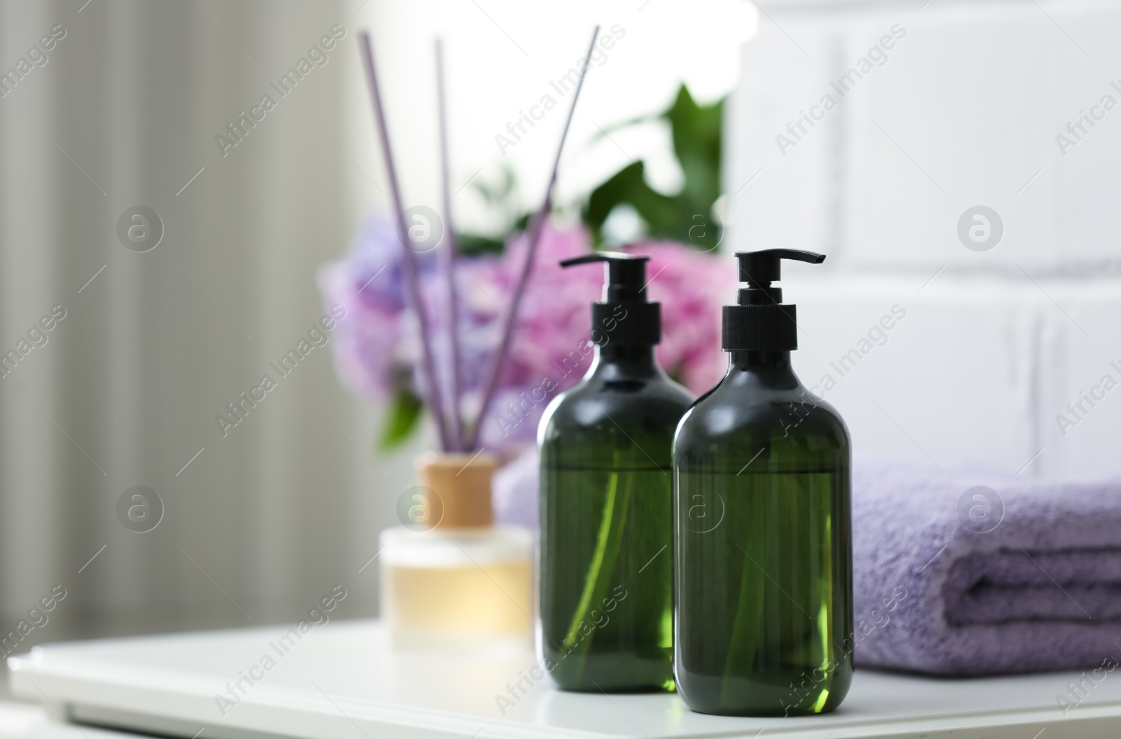 Photo of Soap dispensers and clean towel on white table. Space for text