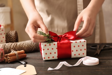 Photo of Woman wrapping Christmas gift at wooden table