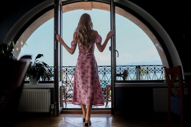 Young woman standing on balcony, back view