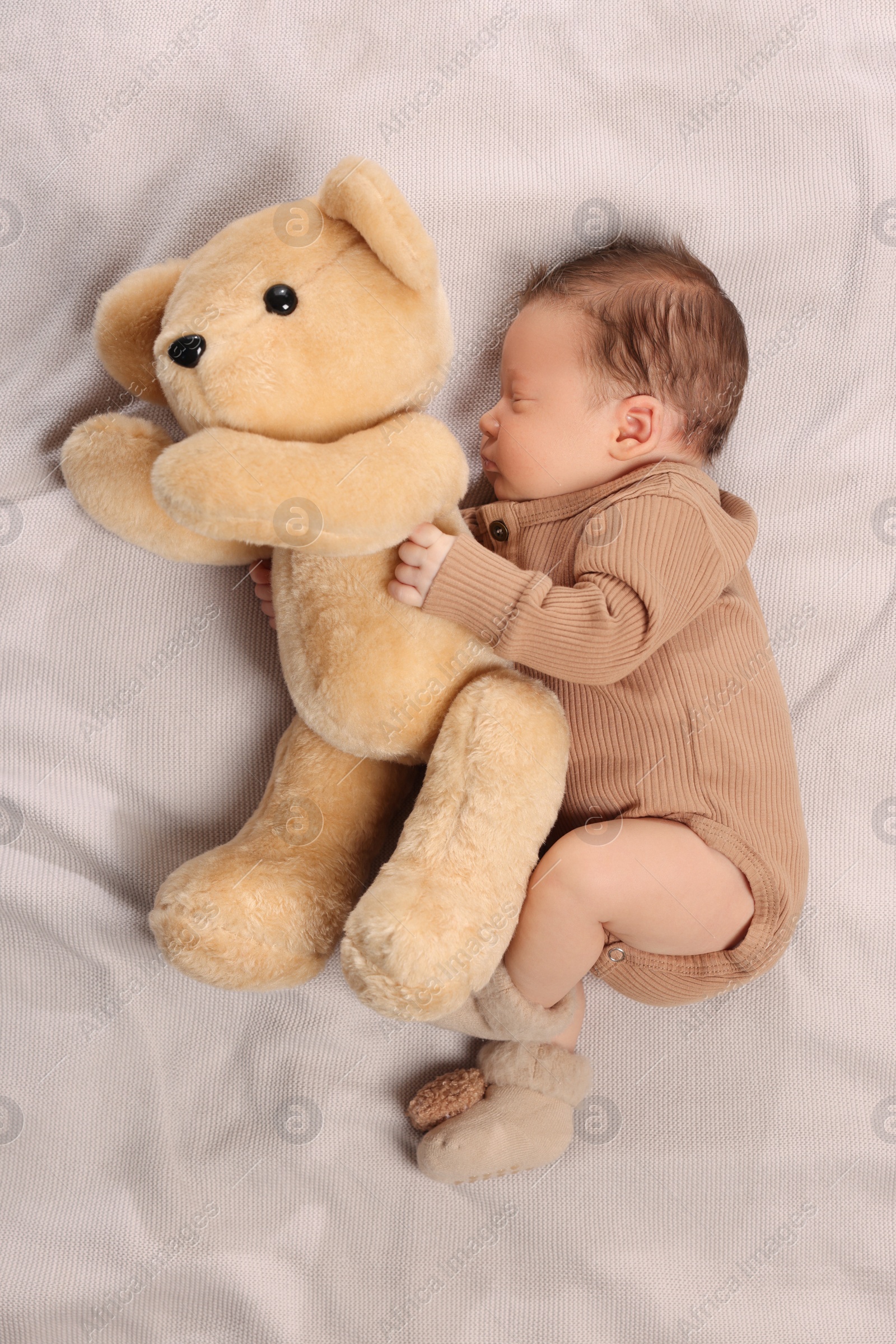 Photo of Cute newborn baby sleeping with toy bear on blanket, top view