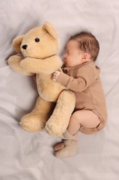 Cute newborn baby sleeping with toy bear on blanket, top view
