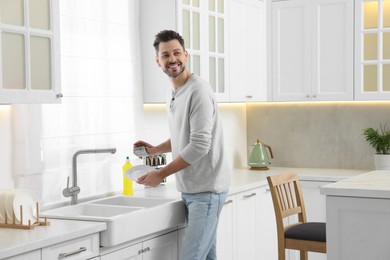 Man washing plate above sink in kitchen