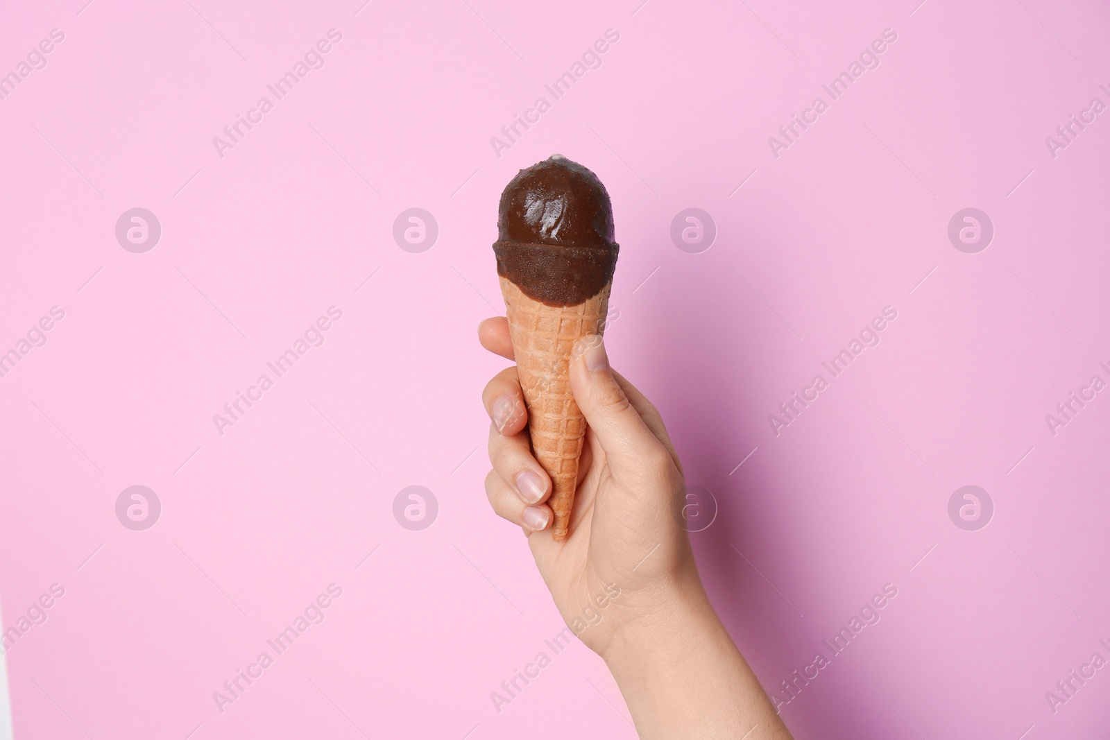 Photo of Woman holding ice cream in waffle cone against color background