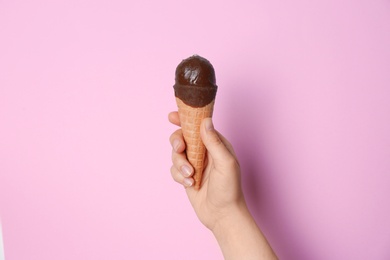 Photo of Woman holding ice cream in waffle cone against color background