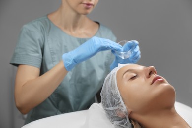 Cosmetologist applying chemical peel product on client's face in salon