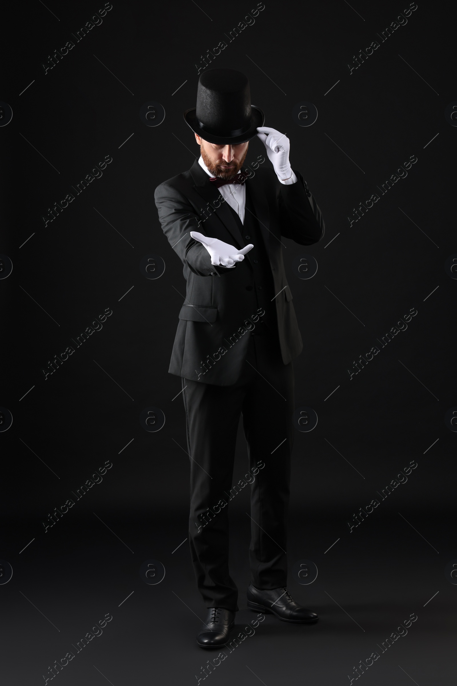 Photo of Magician in top hat on black background