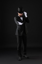 Magician in top hat on black background