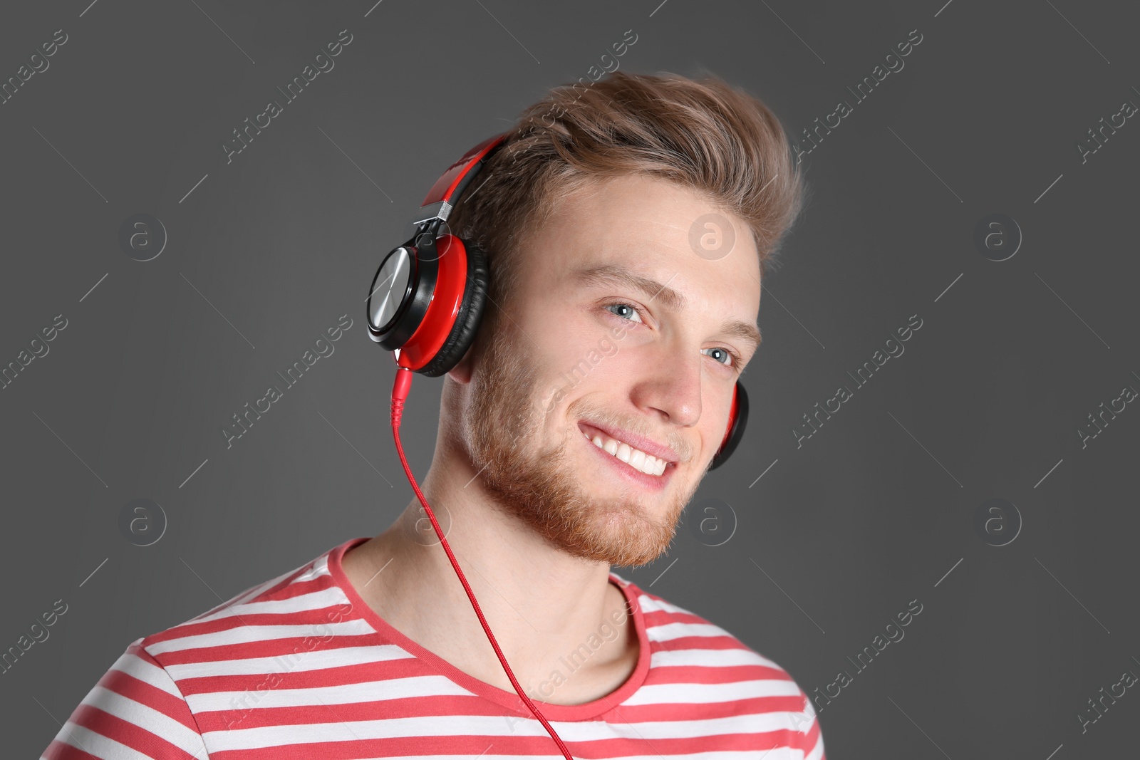 Photo of Handsome young man listening to music with headphones on color background