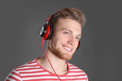 Photo of Handsome young man listening to music with headphones on color background