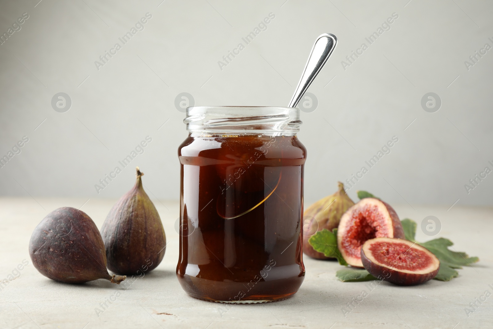 Photo of Jar of tasty sweet jam and fresh figs on light table