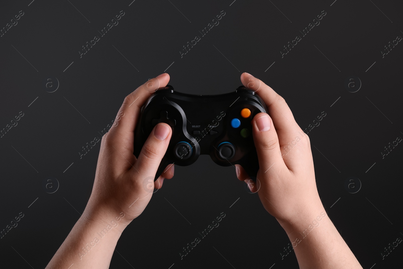 Photo of Woman using wireless game controller on dark background, closeup