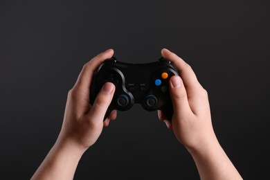 Woman using wireless game controller on dark background, closeup