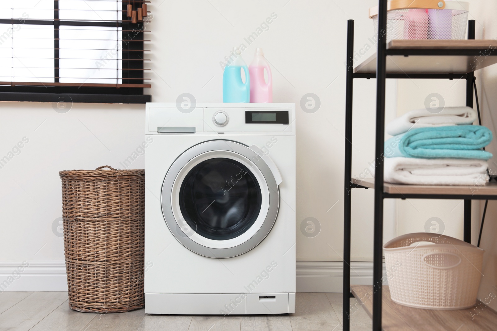 Photo of Modern washing machine in laundry room interior