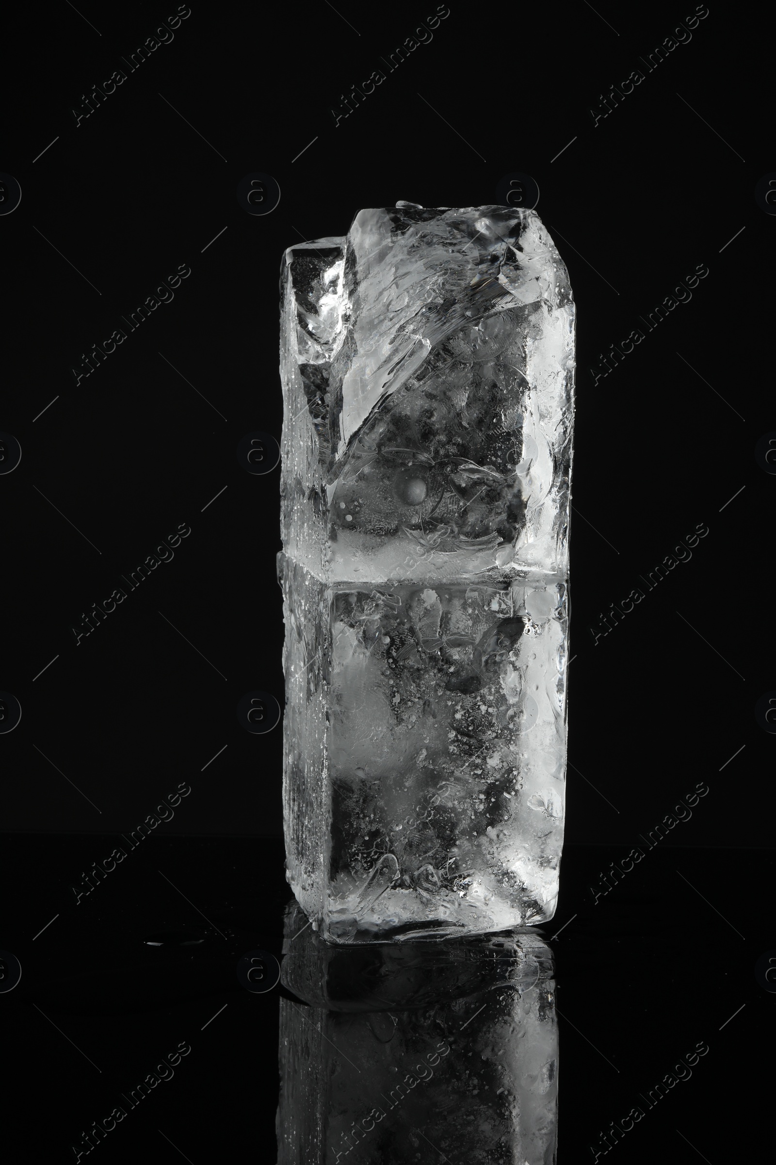 Photo of Blocks of clear ice on black mirror surface