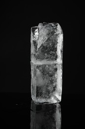 Photo of Blocks of clear ice on black mirror surface