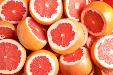 Photo of Many sliced fresh grapefruits as background, top view