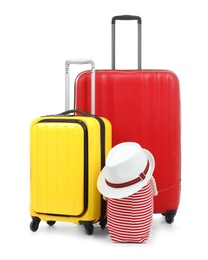 Photo of New suitcases, bag and hat packed for journey on white background