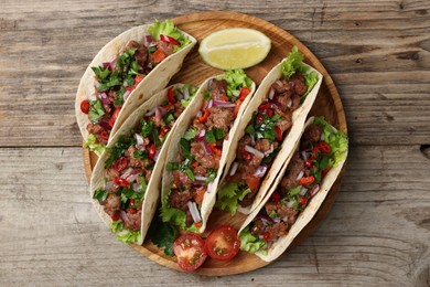 Photo of Delicious tacos with meat, vegetables and lime on wooden table, top view