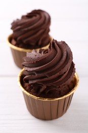 Photo of Delicious chocolate cupcakes on white wooden table, closeup