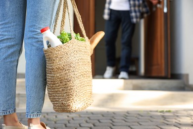 Photo of Helping neighbours. Woman with wicker bag of products visiting man outdoors, closeup