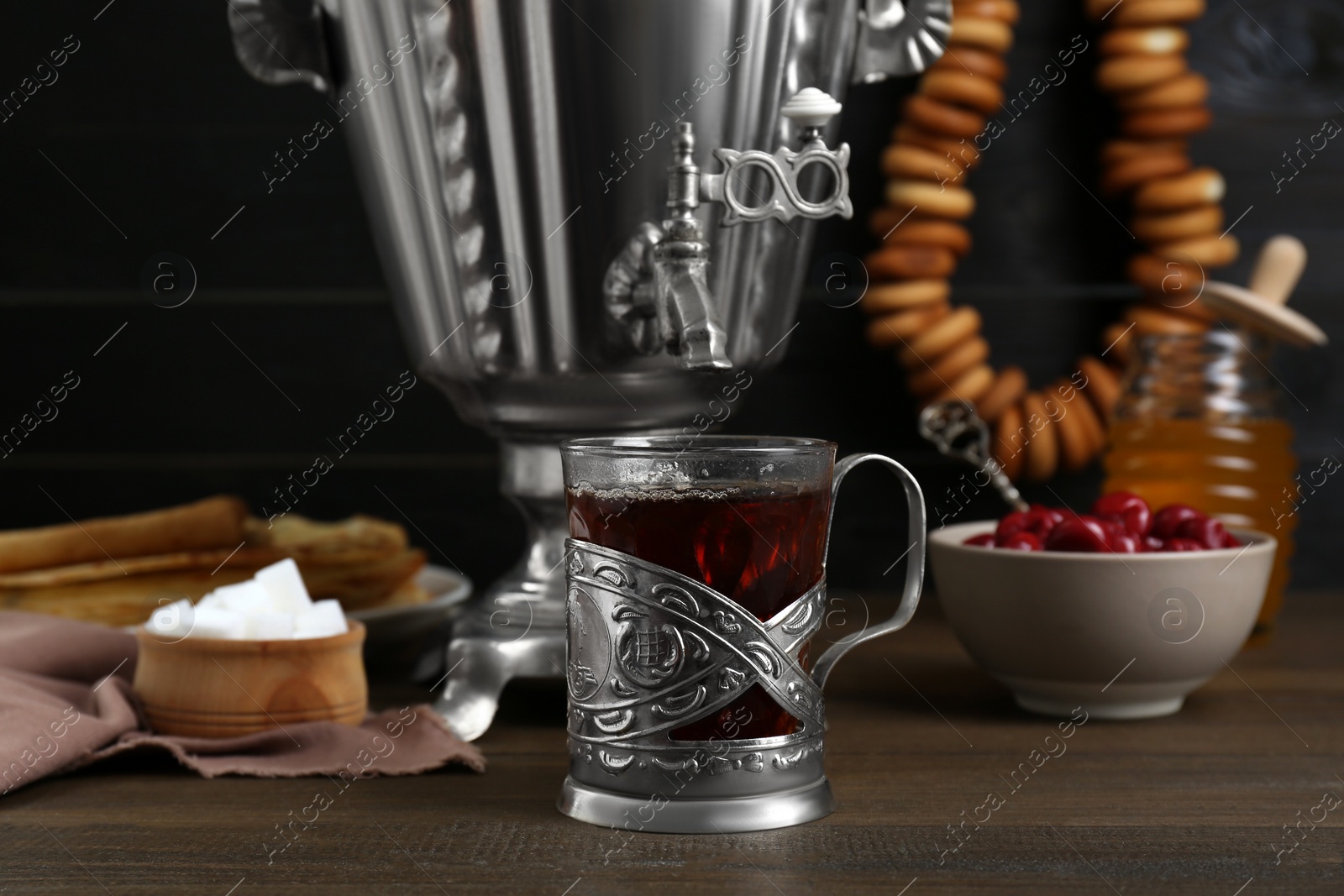 Photo of Metal samovar with cup of tea and treats on wooden table