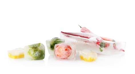 Photo of Fresh vegetables frozen in ice cubes on white background