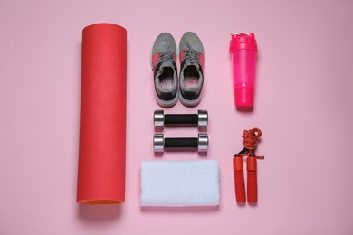 Photo of Exercise mat, dumbbells, towel, skipping rope, shaker and shoes on pink background, flat lay
