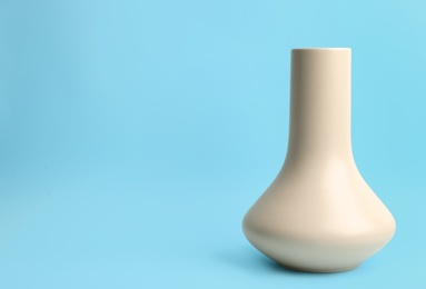 Stylish empty ceramic vase on light blue background, space for text