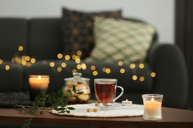 Tea, cookies and decorative elements on wooden table in living room