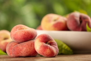 Photo of Fresh ripe donut peaches on wooden table, closeup