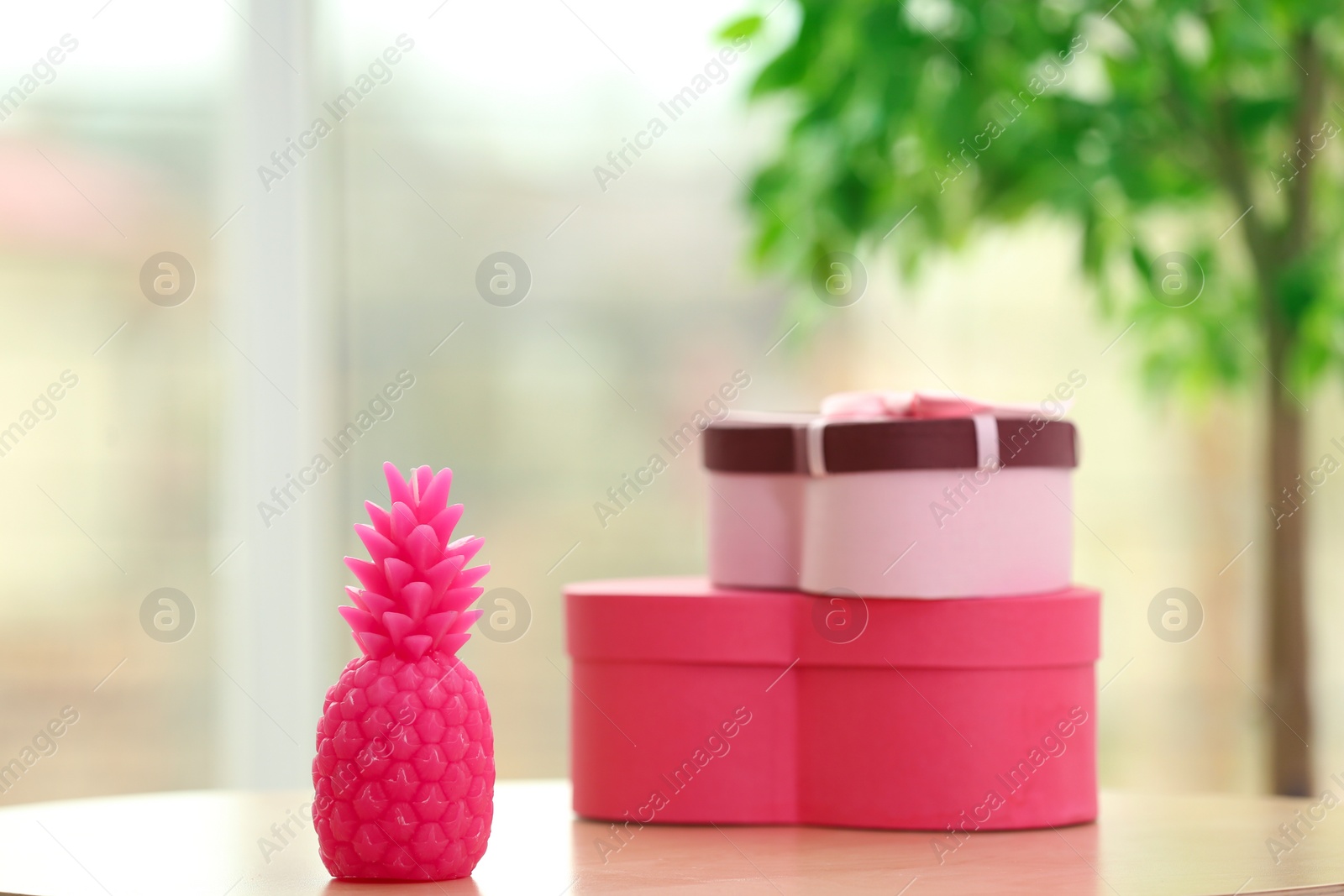 Photo of Stylish pineapple candle and boxes on table indoors. Home decorating idea