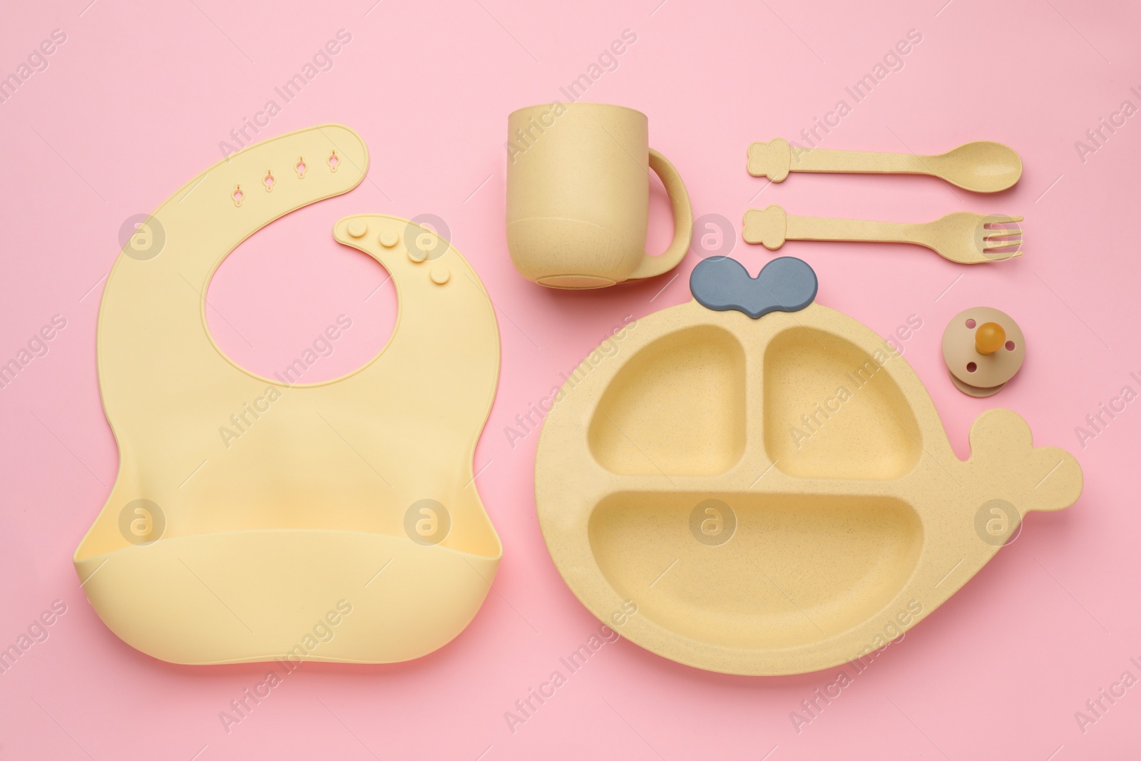 Photo of Flat lay composition with baby feeding accessories and bib on pink background