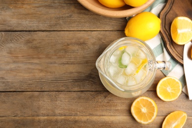 Cool freshly made lemonade and fruits on wooden table, flat lay. Space for text