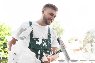 Male cleaner wiping window glass with squeegee from outside