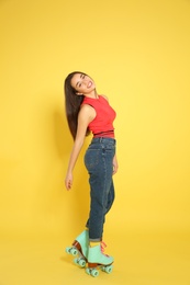 Young woman with roller skates on color background