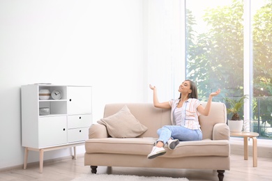 Photo of Young woman relaxing under air conditioner at home