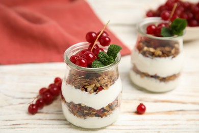 Photo of Delicious yogurt parfait with fresh red currants and mint on white wooden table, closeup