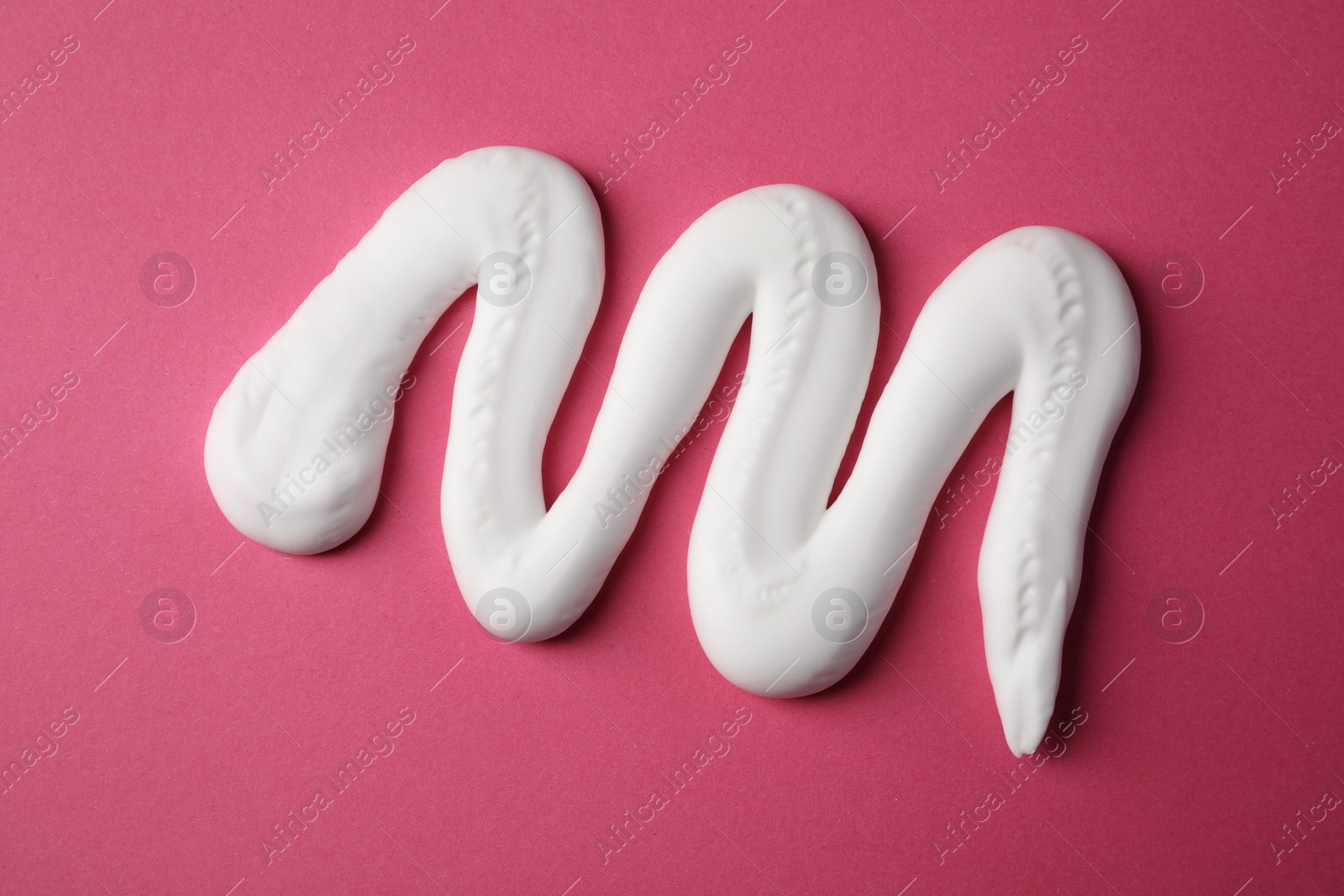 Photo of Sample of shaving foam on pink background, top view