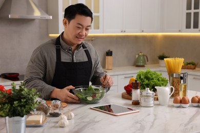 Photo of Man using tablet while cooking in kitchen