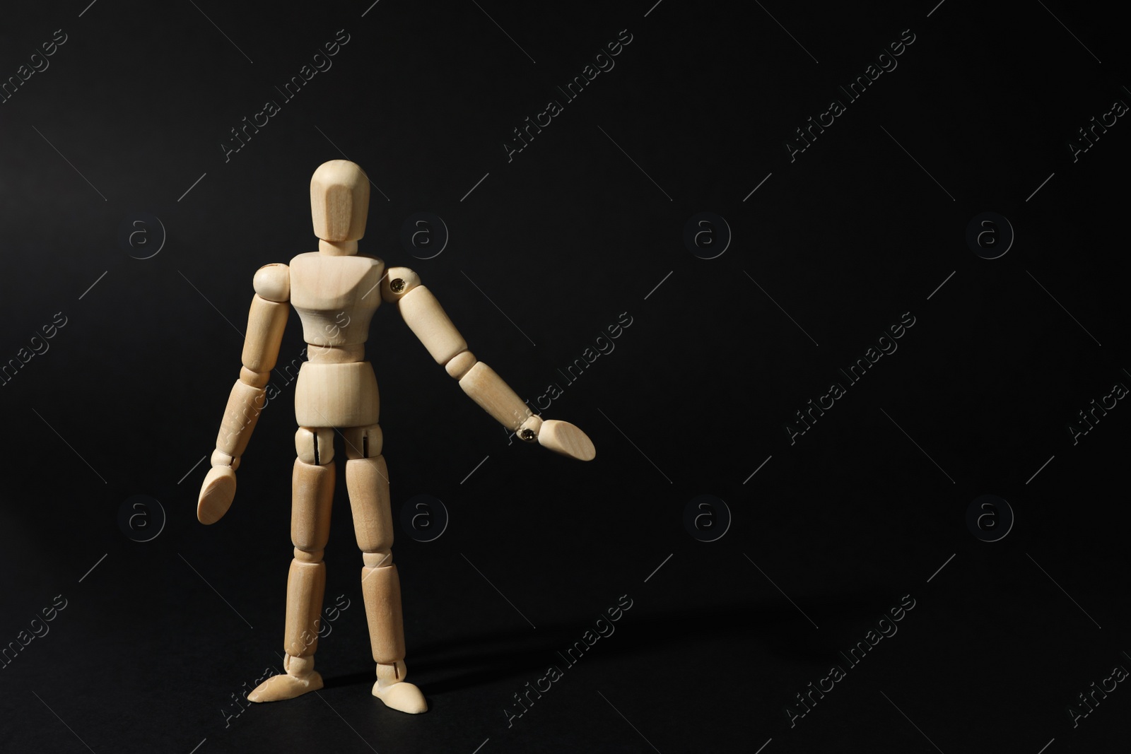 Photo of Wooden human model on black background, space for text. Mini mannequin