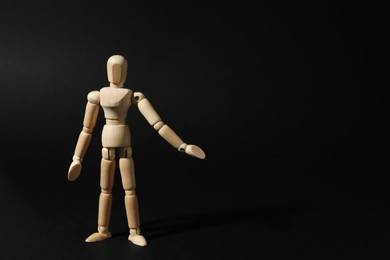 Wooden human model on black background, space for text. Mini mannequin