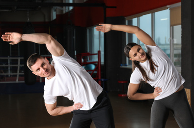 Photo of Couple stretching after workout in modern gym