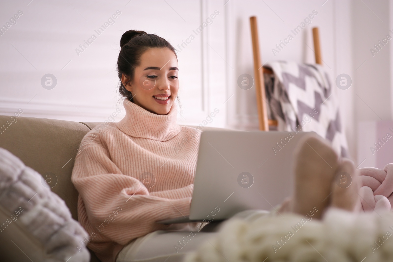 Photo of Beautiful young woman with laptop relaxing at home. Cozy atmosphere