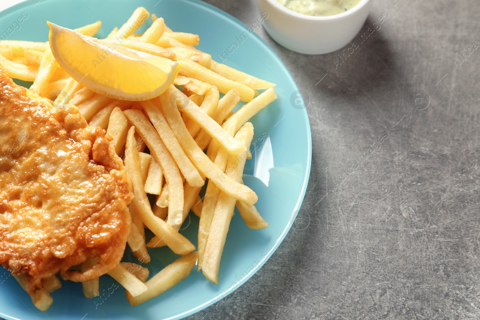 Photo of Plate with British Traditional Fish and potato chips on grey background. Space for text