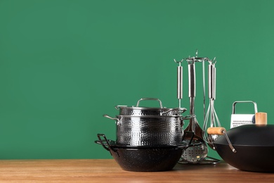 Photo of Set of clean cookware and utensils on table against color background. Space for text