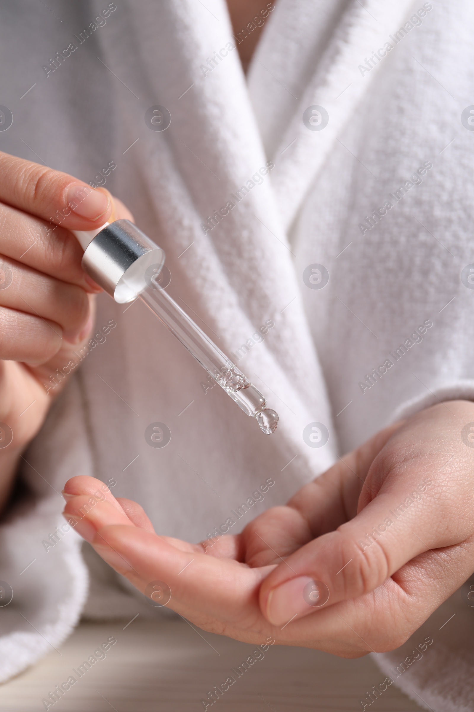 Photo of Woman applying cosmetic serum onto hand, closeup