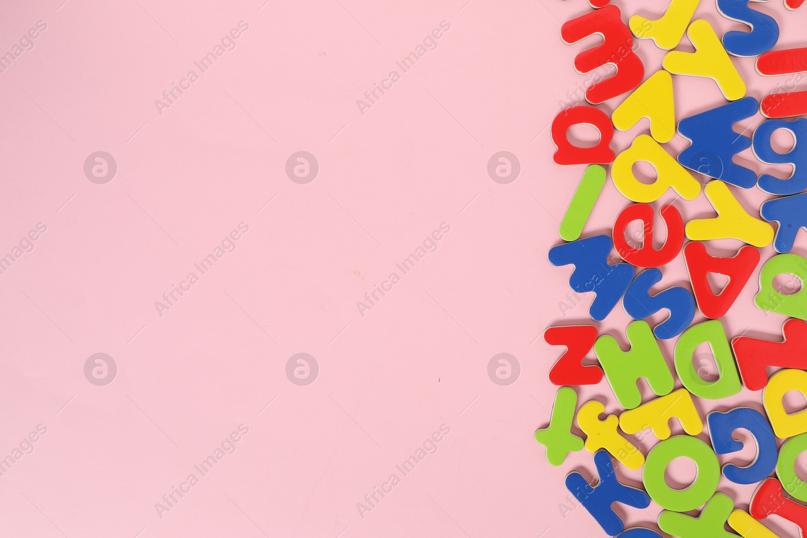 Photo of Learning alphabet. Magnetic letters on pink background, flat lay. Space for text