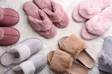 Photo of Many different soft slippers on white faux fur, flat lay