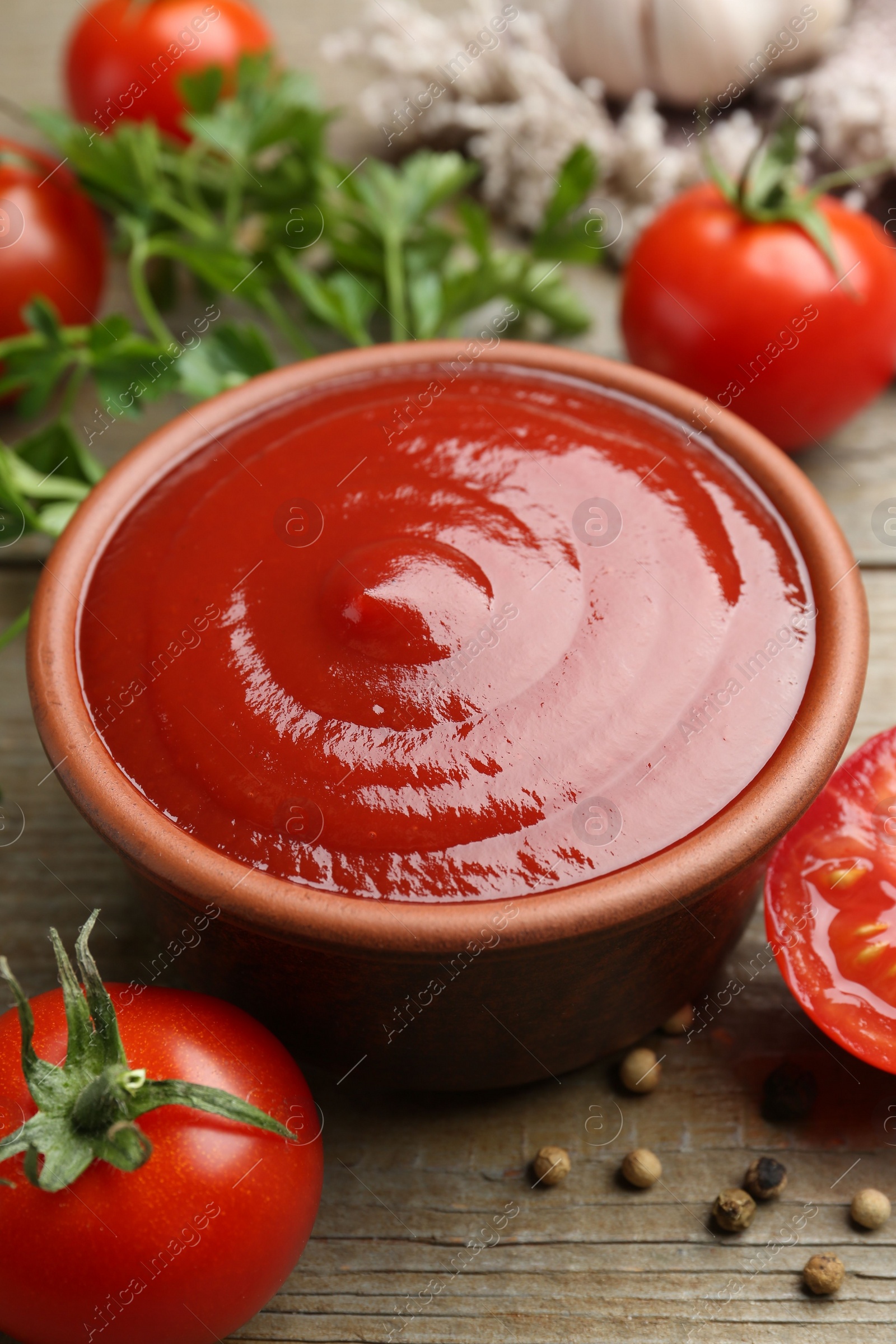 Photo of Tasty ketchup, fresh tomatoes, parsley and spices on wooden table